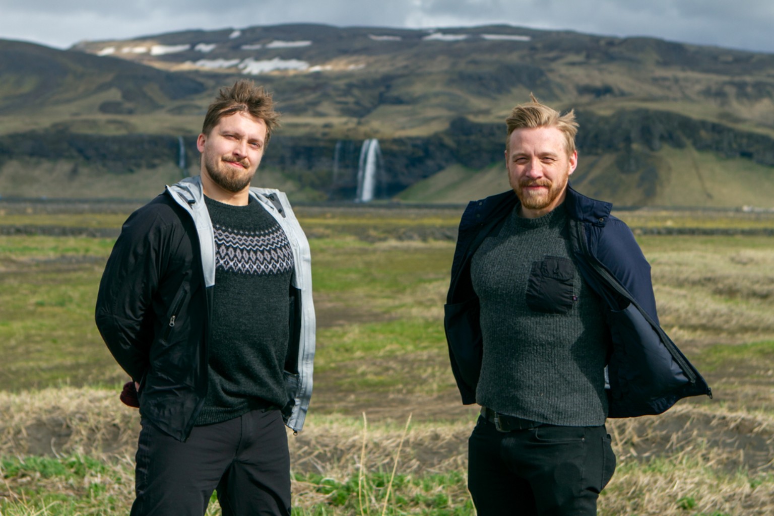 Two colleagues outdoors with an Icelandic waterfall in the background